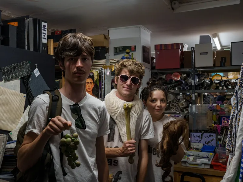 Three customers holding up their finds among the Scrapstore shelves