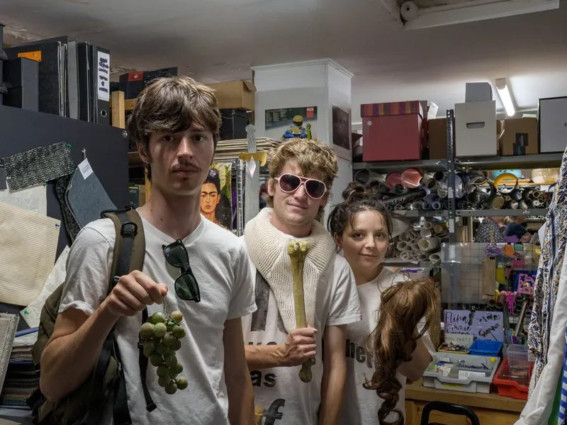 Three customers holding up their finds among the Scrapstore shelves