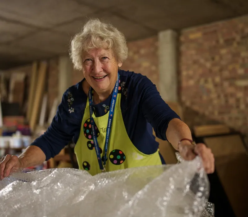 A smiling volunteer unpacking a delivery of donated materials