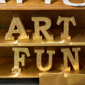 Gold ART FUN letters on a shelf in the Scrapstore lobby
